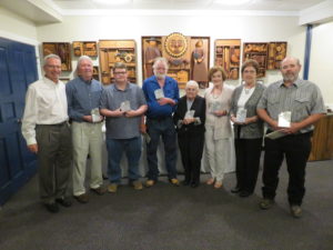 Group of men and women standing together holding plaques in recognition ceremony.