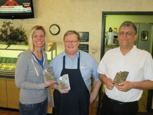 Three people holding awards and smiling inside a restaurant setting.