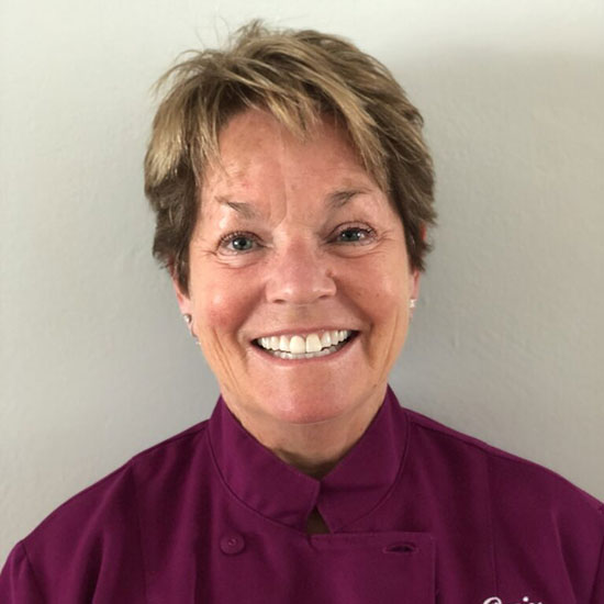 Smiling woman chef in purple chef coat professional headshot portrait.