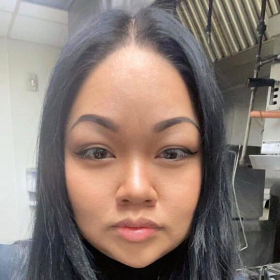 Young woman with long dark hair in professional headshot taken in commercial kitchen.