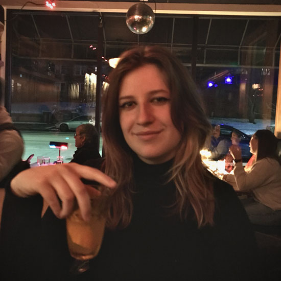 Woman with long brown hair holding drink at evening restaurant or bar event.