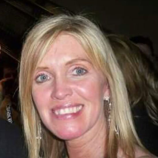 Close-up of smiling blonde woman in an evening setting wearing earrings.