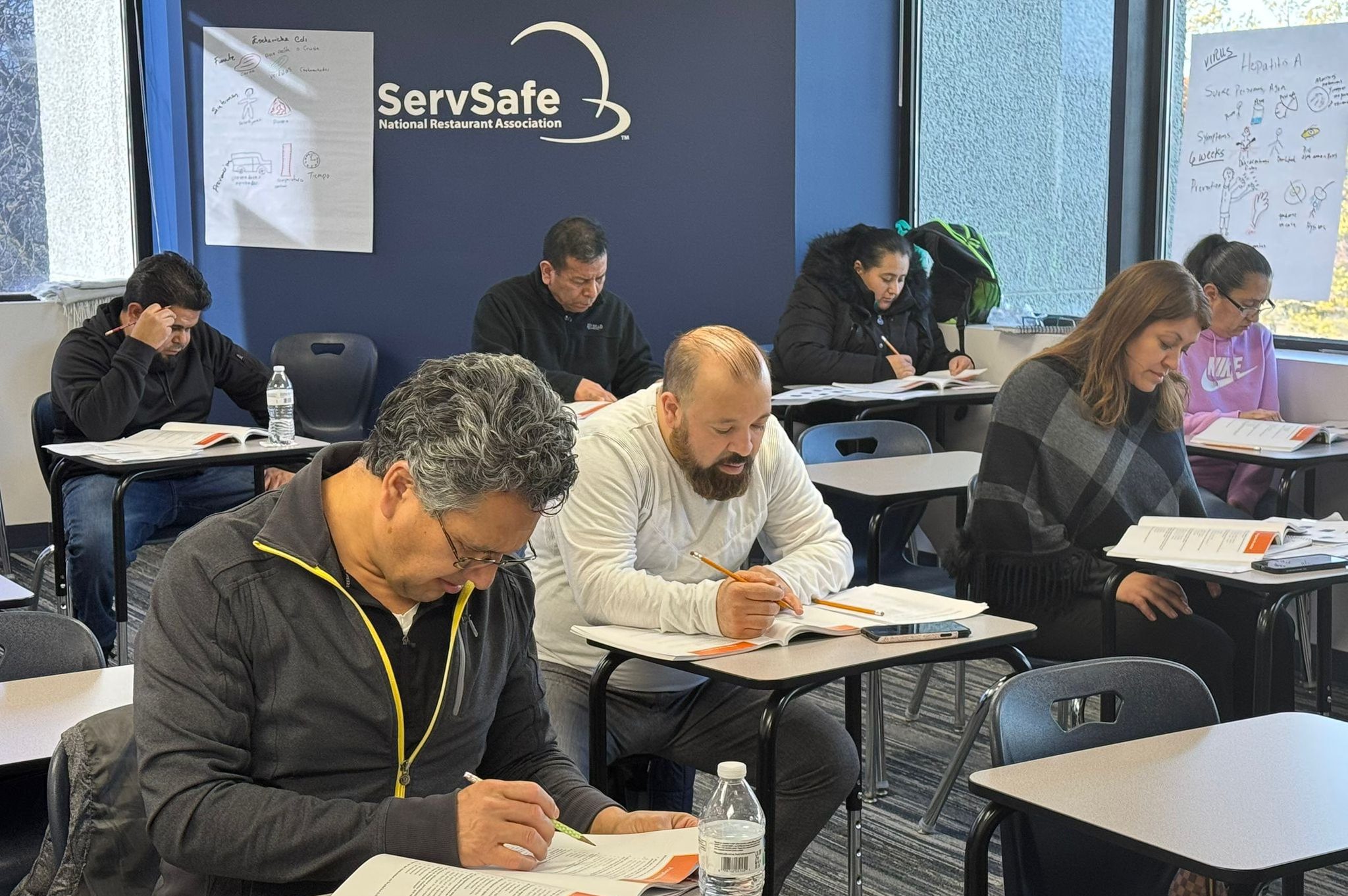 Students seated in classroom taking notes during ServSafe training session.