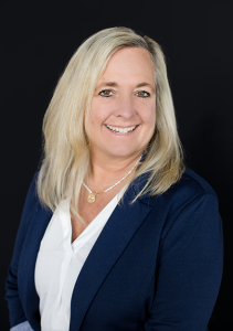 Professional headshot of smiling woman with long blonde hair wearing a navy blazer over a white blouse.