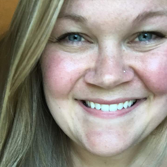 Close-up headshot of a smiling woman with straight blonde hair and blue eyes.
